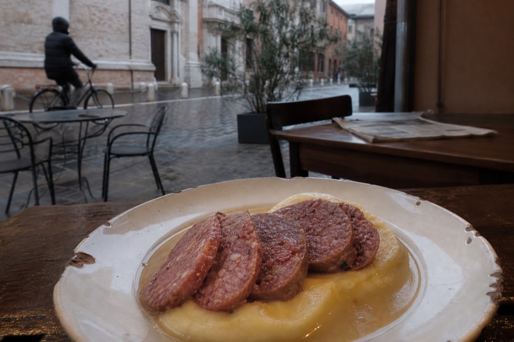 Sliced cotechino sausage with potato purée on a rustic plate