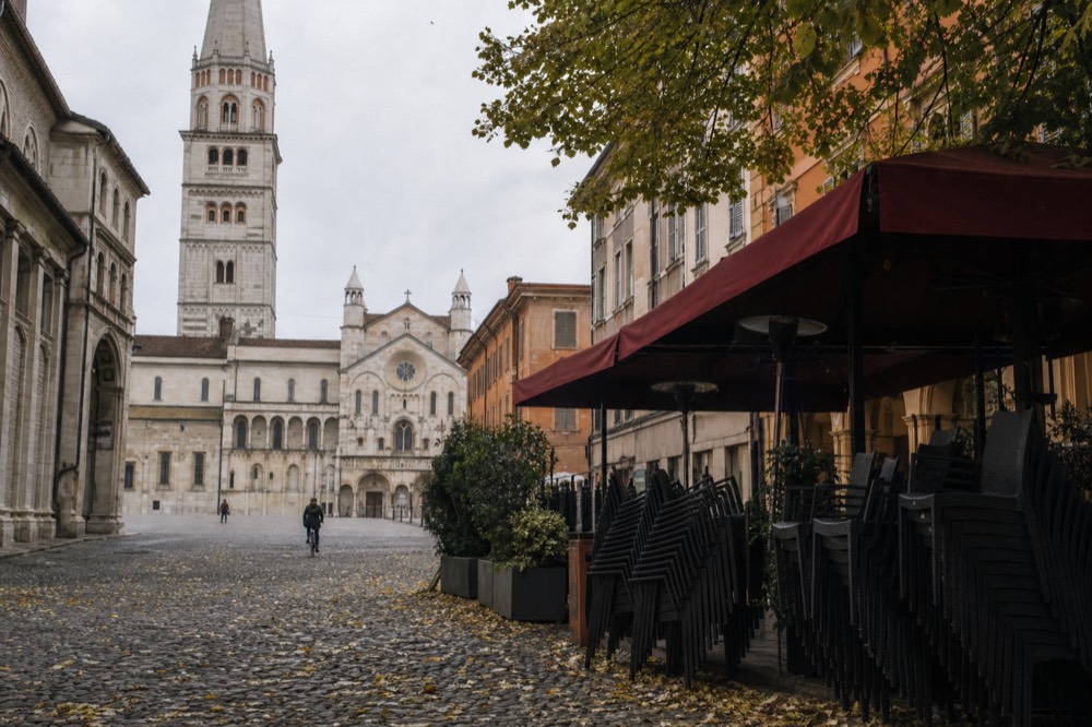 A quiet Sunday piazza in Modena with a restaurant terrace closed