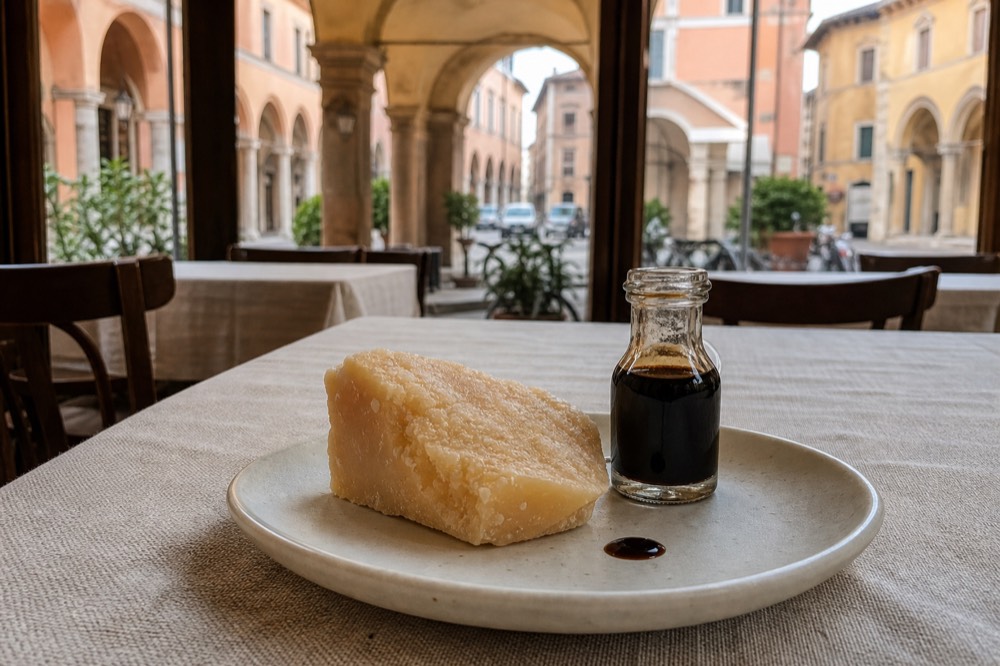 A diner's plate with a piece of Parmigiano Reggiano and a small bottle of Traditional Balsamic