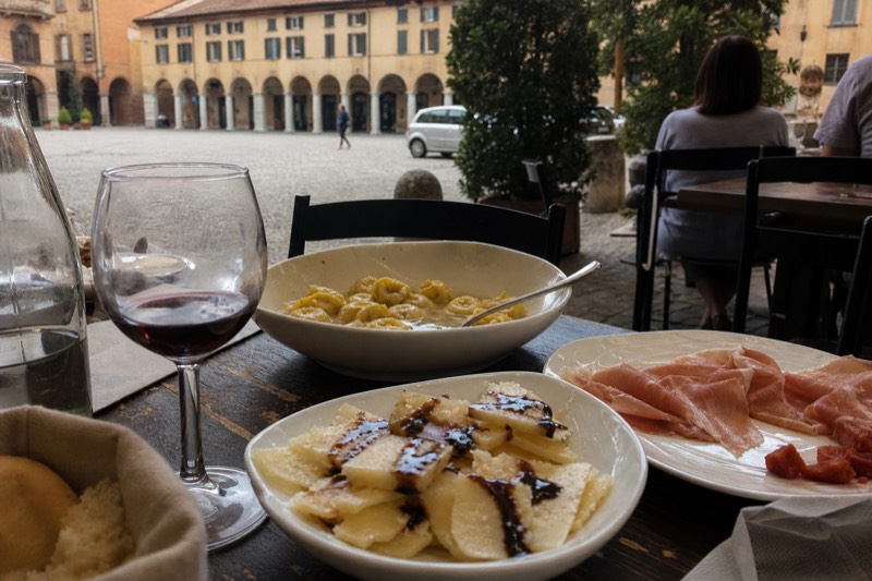 A spread of Modena specialties from a food tour: traditional balsamic vinegar drizzled over cheese, cured meats, fresh tortellini and a glass of lambrusco.